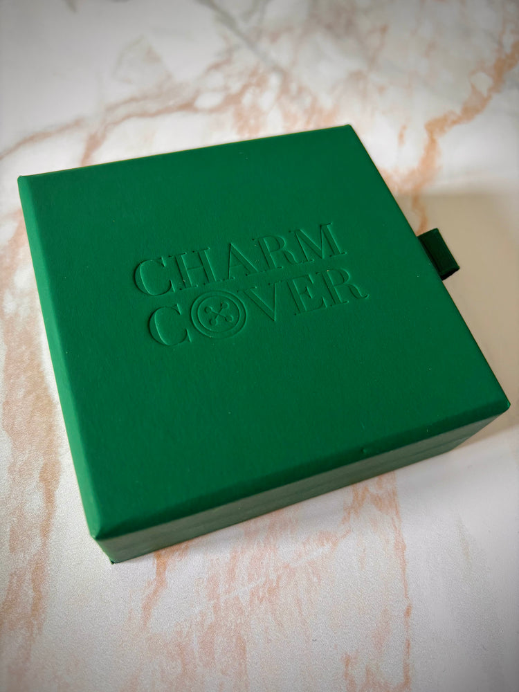 Boîte cadeau verte Charm Cover avec logo gaufré sur fond marbre