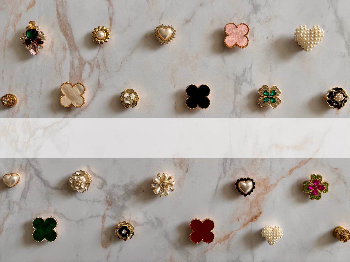 Collection n°1 de bijoux de bouton Charm Cover disposés sur marbre blanc