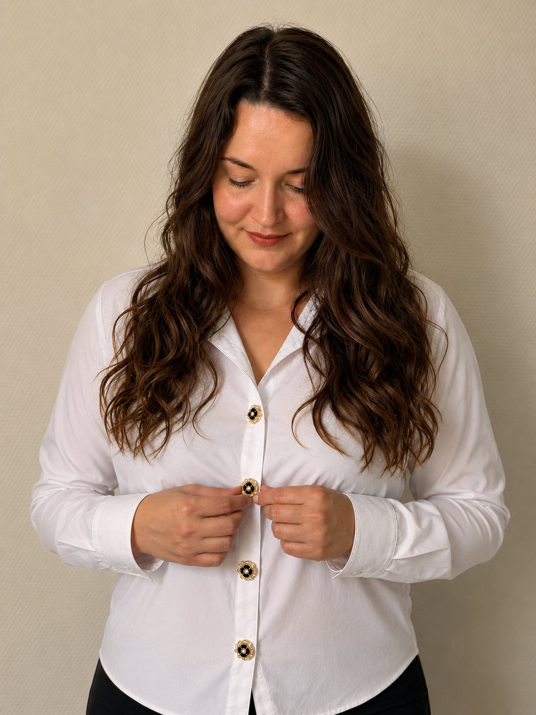 Clémence fondatrice de Charm Cover clipsant un bijou de bouton sur une chemise blanche